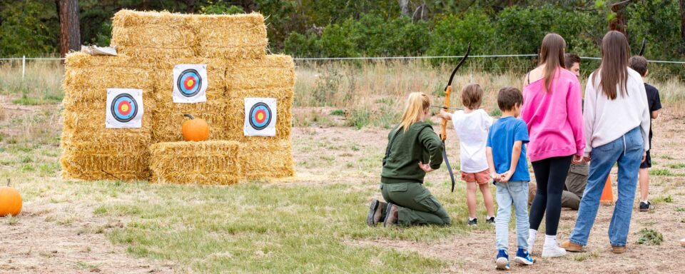 park ranger teaching children how to practice archery